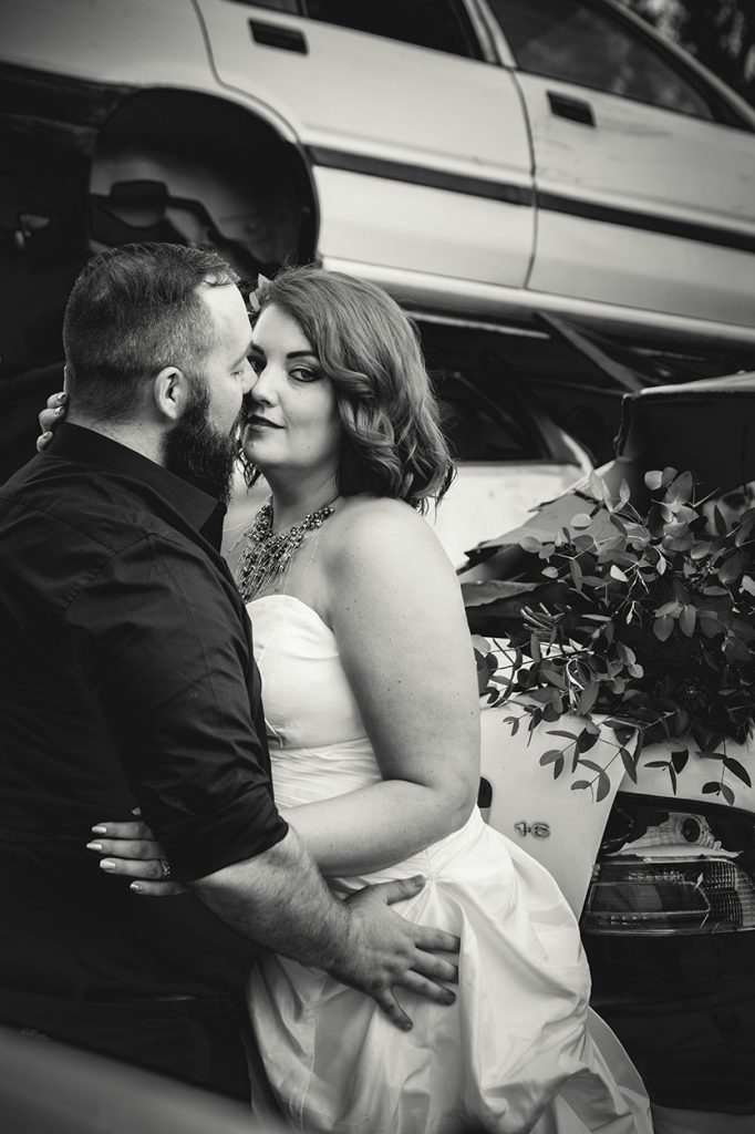 Wedding photography in scrapyard bride sneaking a look at camera by Bloemfontein photographer Unix photography