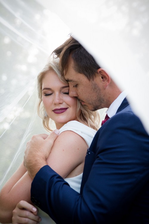 Wedding photography of bridal couple snuggling in veil by Unix photography Wedding photography of bridal couple snuggling in veil by Unix photography