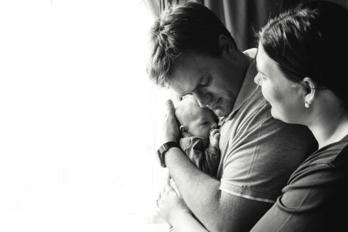 mother and father cuddling newborn black and white photo by Unix photography Belly to baby photography mother and father cuddling newborn black and white photo by Unix photography